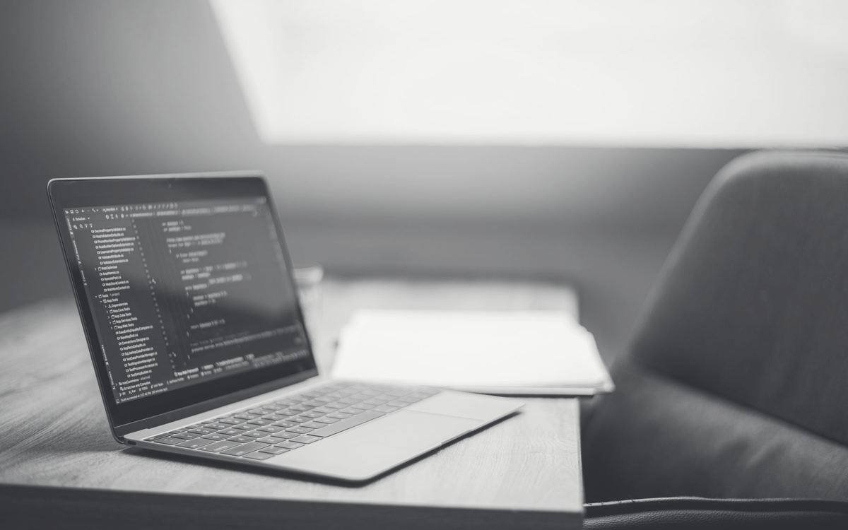 Notebook aberto com código sobre uma mesa de trabalho vazia